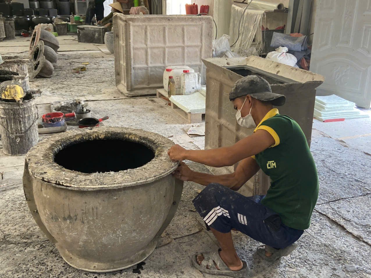 Worker finishing a large cast fiberstone pot, Vietnam factory